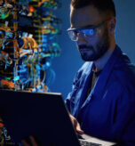 In glasses. Young man is working with internet equipment and wires in server room.